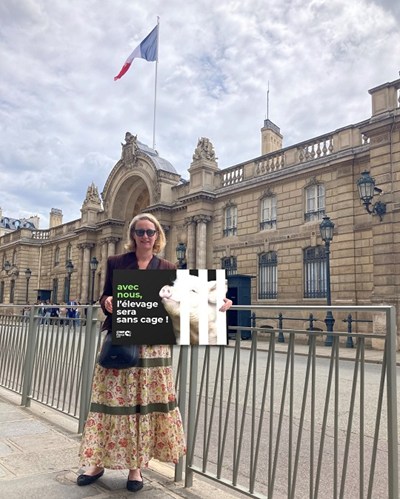 Leopoldine Charbonneaux Directrice CIWF France devant le Palais de l'Elysée avec la carte postale grand format avec nous l'élevage sera sans cage